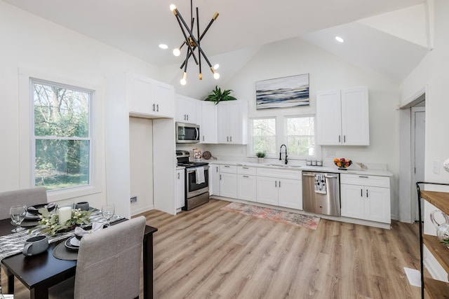 kitchen featuring a sink, white cabinetry, light countertops, appliances with stainless steel finishes, and an inviting chandelier