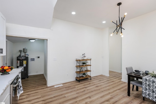 dining area featuring light wood-style flooring, visible vents, baseboards, and electric water heater