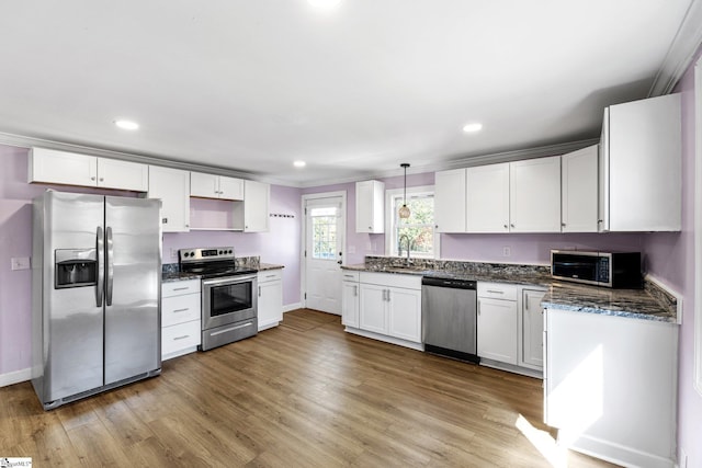 kitchen with a sink, appliances with stainless steel finishes, wood finished floors, and white cabinets