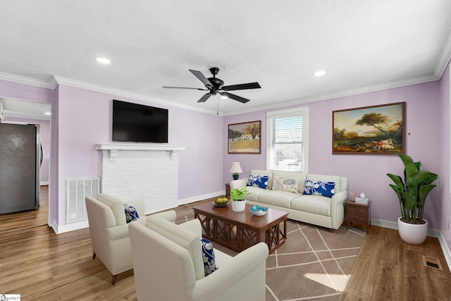 living area with ornamental molding, visible vents, baseboards, and wood finished floors