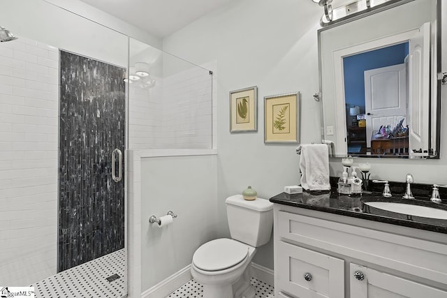 bathroom featuring a stall shower, vanity, toilet, and baseboards