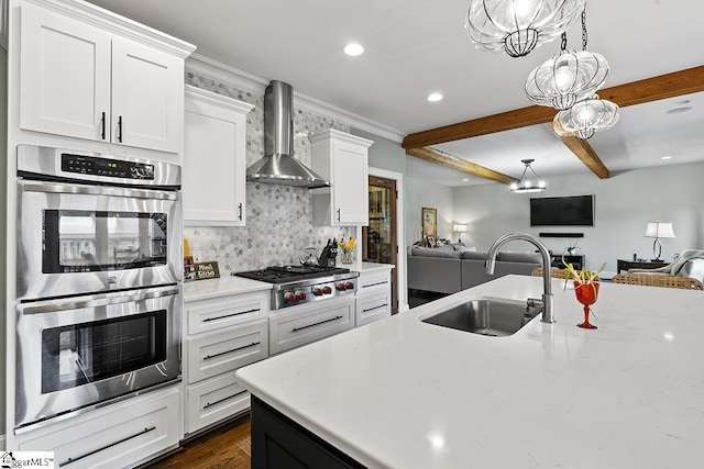 kitchen featuring stainless steel appliances, a sink, open floor plan, beam ceiling, and wall chimney exhaust hood