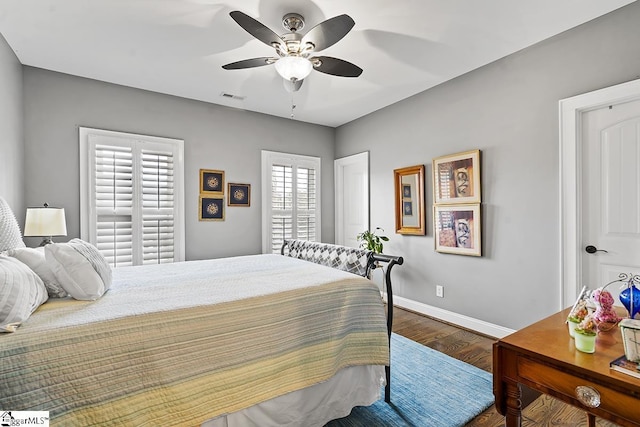 bedroom featuring visible vents, ceiling fan, baseboards, and wood finished floors