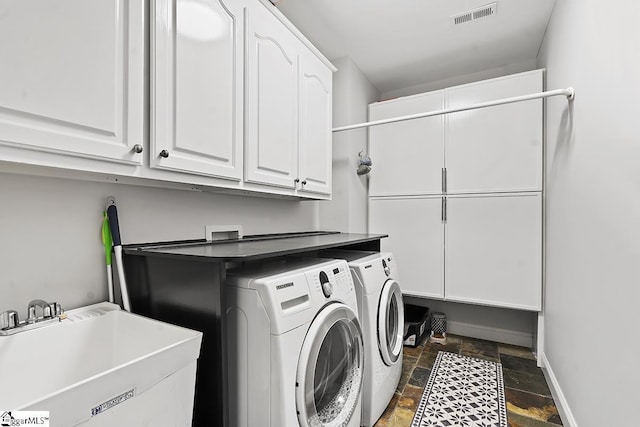 clothes washing area featuring cabinet space, stone tile floors, visible vents, washer and dryer, and a sink