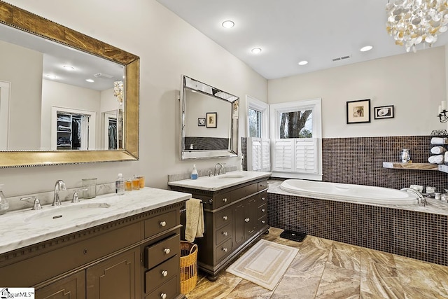 bathroom with a bath, visible vents, two vanities, and a sink