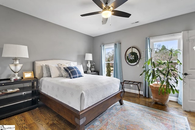 bedroom with a ceiling fan, wood finished floors, visible vents, and baseboards