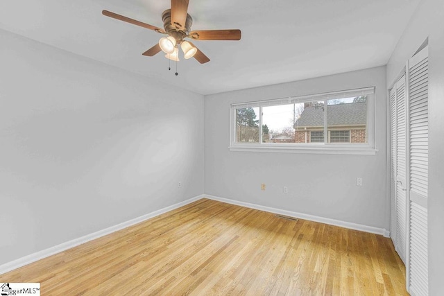 spare room with ceiling fan, wood finished floors, visible vents, and baseboards