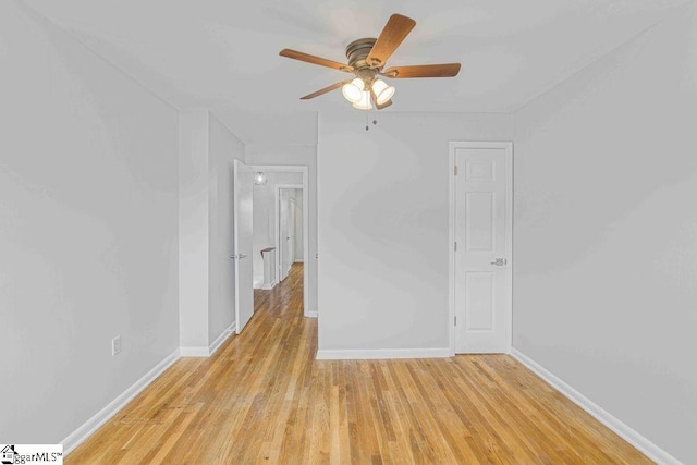 empty room featuring ceiling fan, light wood-type flooring, and baseboards