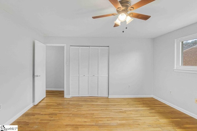 unfurnished bedroom featuring light wood-style floors, a ceiling fan, baseboards, and a closet