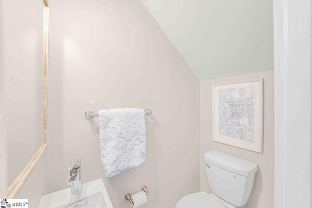 bathroom featuring toilet, vaulted ceiling, and a sink