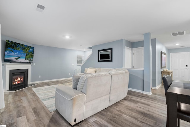 living room with visible vents, light wood-style flooring, and baseboards