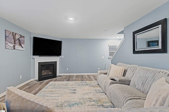 living room featuring recessed lighting, baseboards, wood finished floors, and a glass covered fireplace