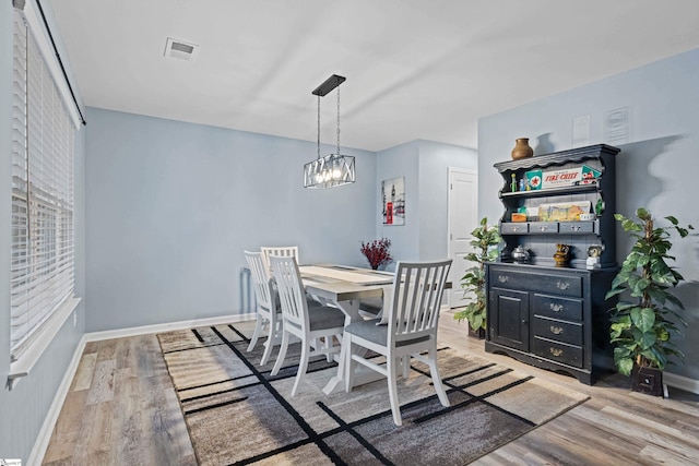 dining room featuring light wood-style floors, baseboards, visible vents, and an inviting chandelier