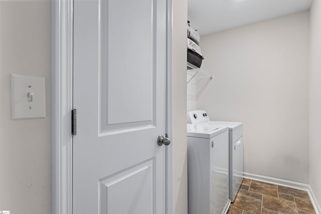 clothes washing area featuring baseboards, laundry area, independent washer and dryer, and stone finish flooring