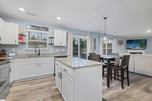 kitchen featuring stainless steel range with electric cooktop, visible vents, a sink, and light wood finished floors