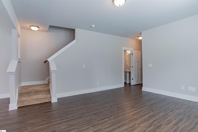 unfurnished living room featuring dark wood-type flooring, a sink, stairway, and baseboards