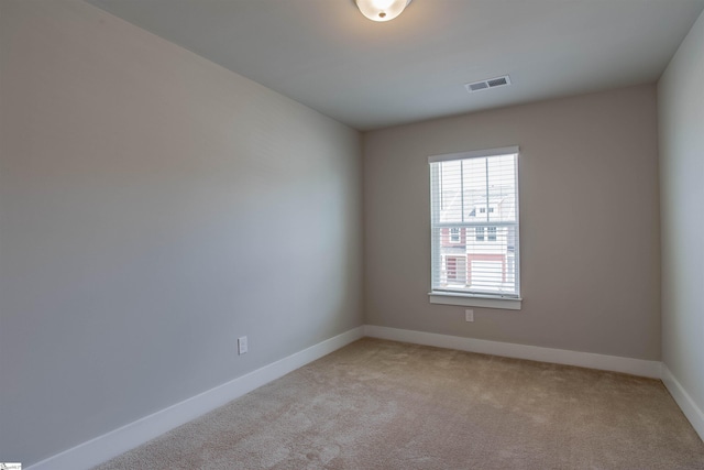 spare room featuring baseboards, visible vents, and light colored carpet