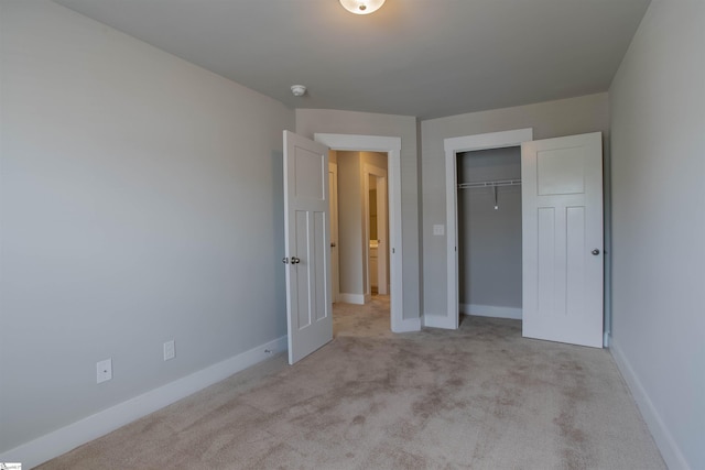 unfurnished bedroom featuring a closet, light colored carpet, and baseboards