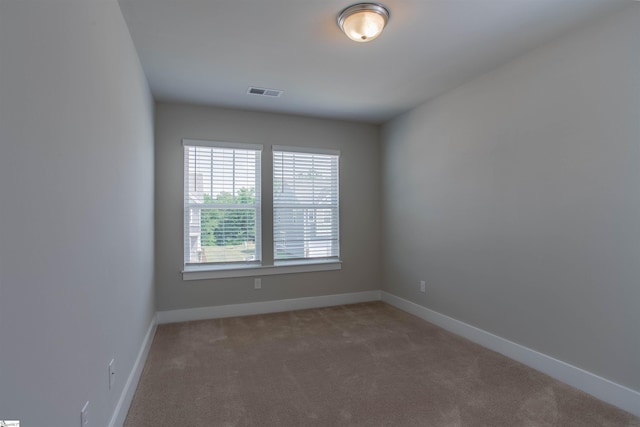 spare room with carpet flooring, visible vents, and baseboards