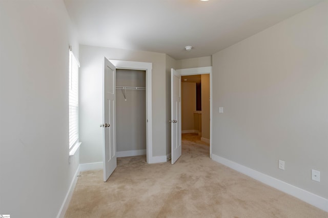 unfurnished bedroom with baseboards, a closet, and light colored carpet