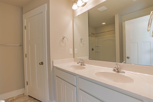 full bathroom with double vanity, baseboards, walk in shower, and a sink