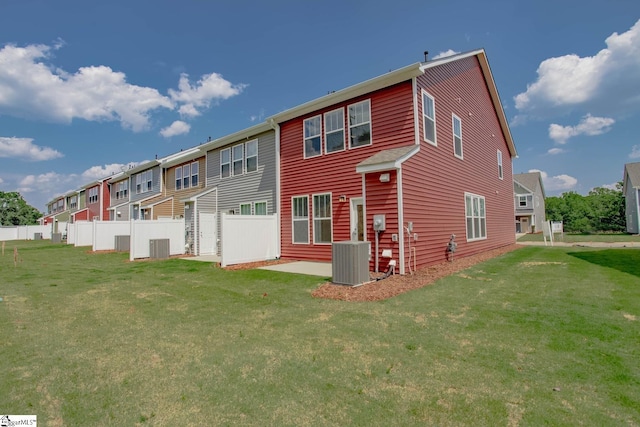 rear view of house with central air condition unit, a residential view, fence, and a lawn