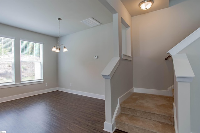 stairway featuring wood finished floors, visible vents, baseboards, and an inviting chandelier