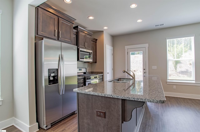 kitchen featuring wood finished floors, a sink, visible vents, appliances with stainless steel finishes, and a center island with sink