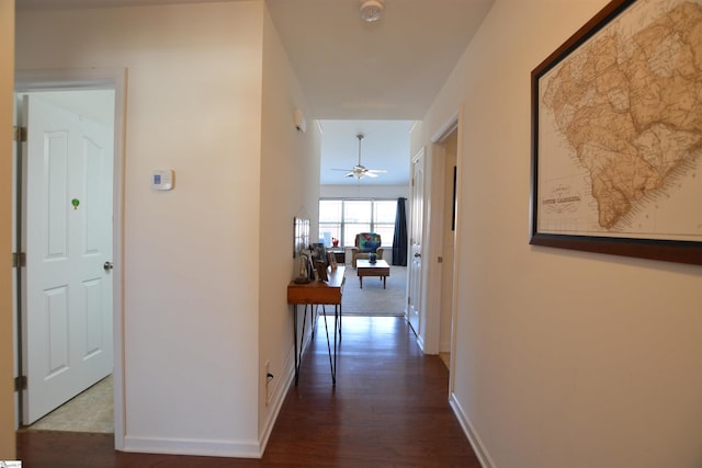 hallway featuring dark wood-style floors and baseboards