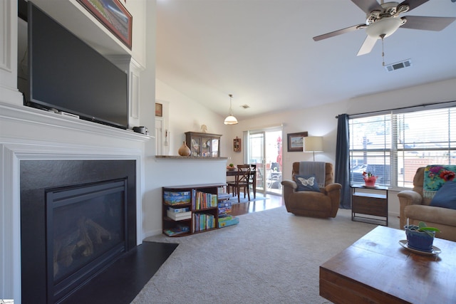 living room featuring lofted ceiling, ceiling fan, carpet floors, a fireplace with flush hearth, and visible vents