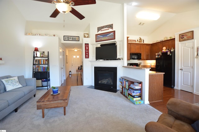 living area featuring ceiling fan, high vaulted ceiling, wood finished floors, and a fireplace with flush hearth