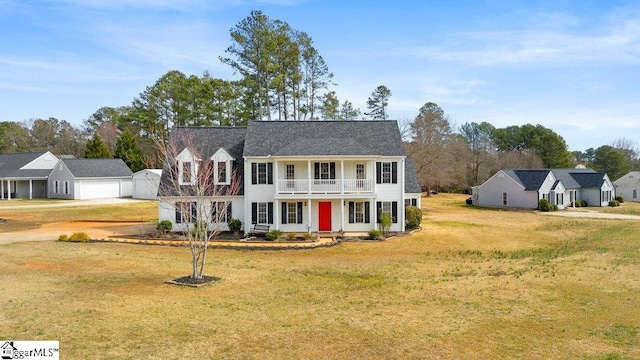 view of front of home featuring a garage, a front yard, a balcony, and an outbuilding