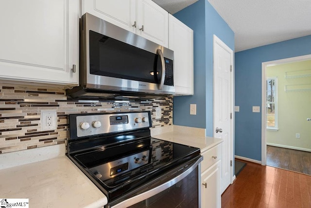 kitchen with stainless steel appliances, backsplash, dark wood-type flooring, white cabinets, and baseboards