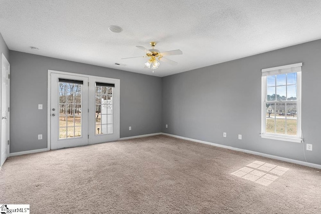 empty room with carpet, visible vents, ceiling fan, a textured ceiling, and baseboards