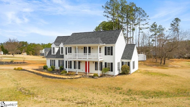 view of front of property featuring driveway, a balcony, roof with shingles, covered porch, and a front lawn