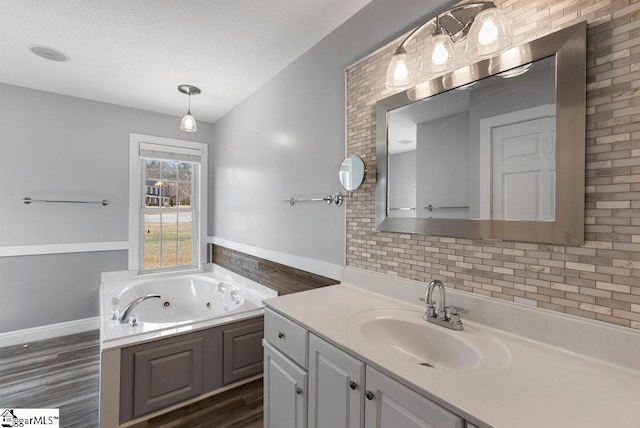 full bathroom with wood finished floors, a textured ceiling, a whirlpool tub, and vanity