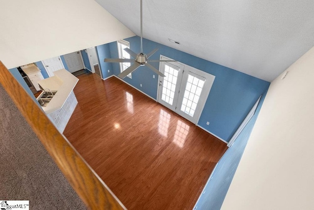 unfurnished living room with lofted ceiling, a sink, a textured ceiling, and wood finished floors