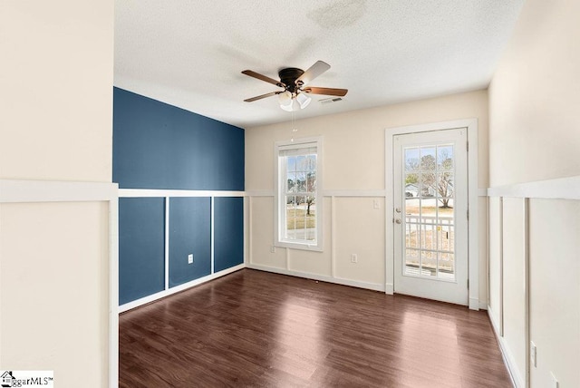 spare room with a textured ceiling, visible vents, wood finished floors, and a ceiling fan