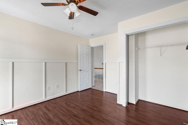 unfurnished bedroom featuring a textured ceiling, a closet, wainscoting, and wood finished floors