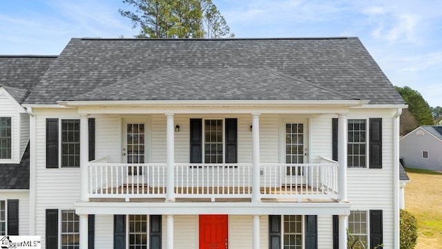 view of front of property with a shingled roof and a balcony