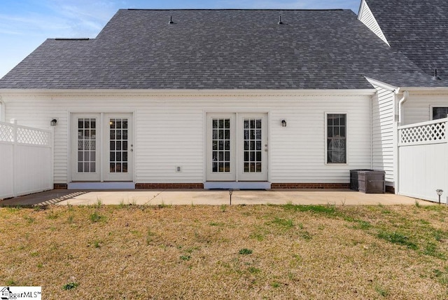 back of property with a shingled roof, a patio, and french doors