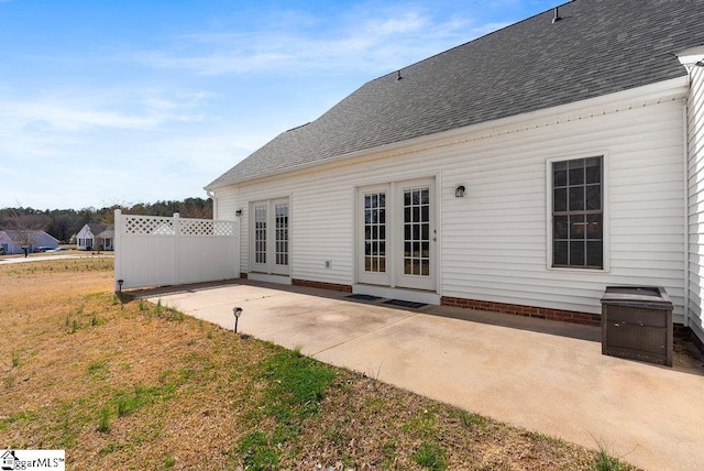 back of house with roof with shingles, fence, a patio, and french doors