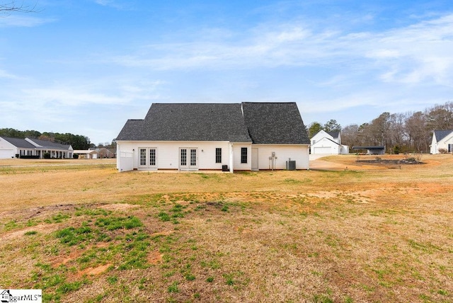 view of front of property featuring french doors, central AC, a front lawn, and roof with shingles