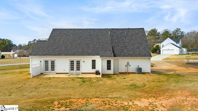 back of property with french doors, a yard, a detached garage, and central AC unit