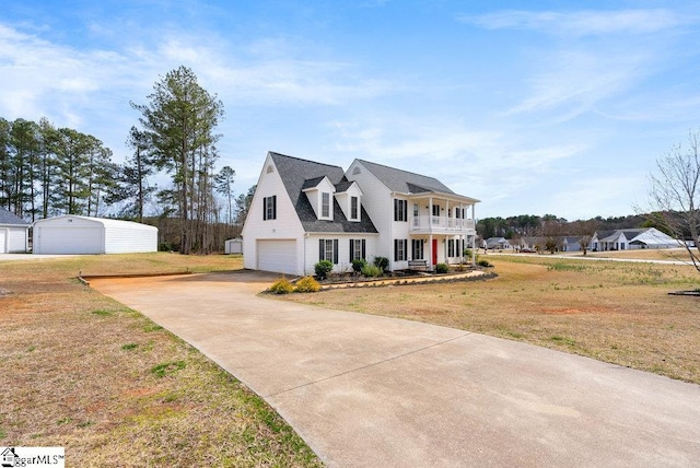 view of front of property with a front yard, a detached garage, and a balcony