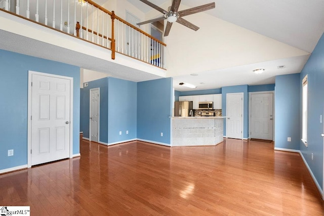 unfurnished living room with a high ceiling, wood finished floors, and baseboards