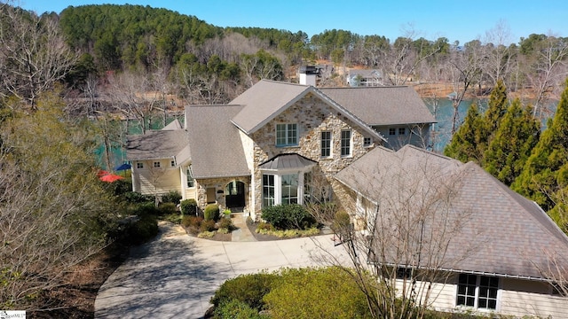 view of front of house featuring driveway, stone siding, and a chimney