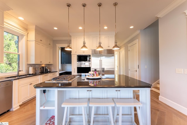 kitchen with dark countertops, crown molding, a kitchen bar, and built in appliances