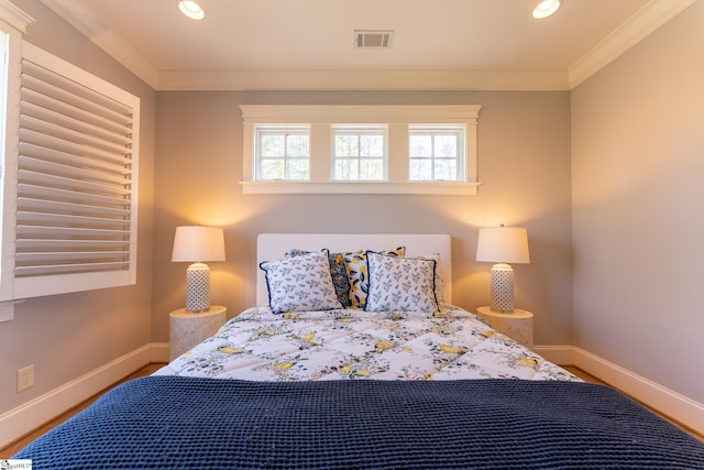 bedroom with visible vents, crown molding, baseboards, and multiple windows