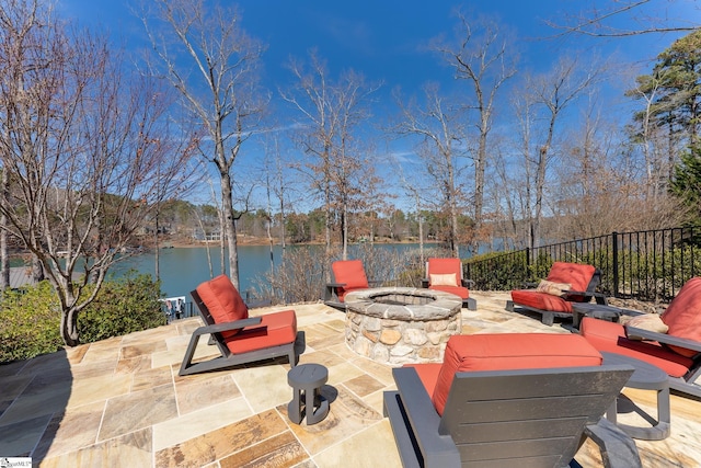 view of patio / terrace featuring an outdoor fire pit, a water view, and fence